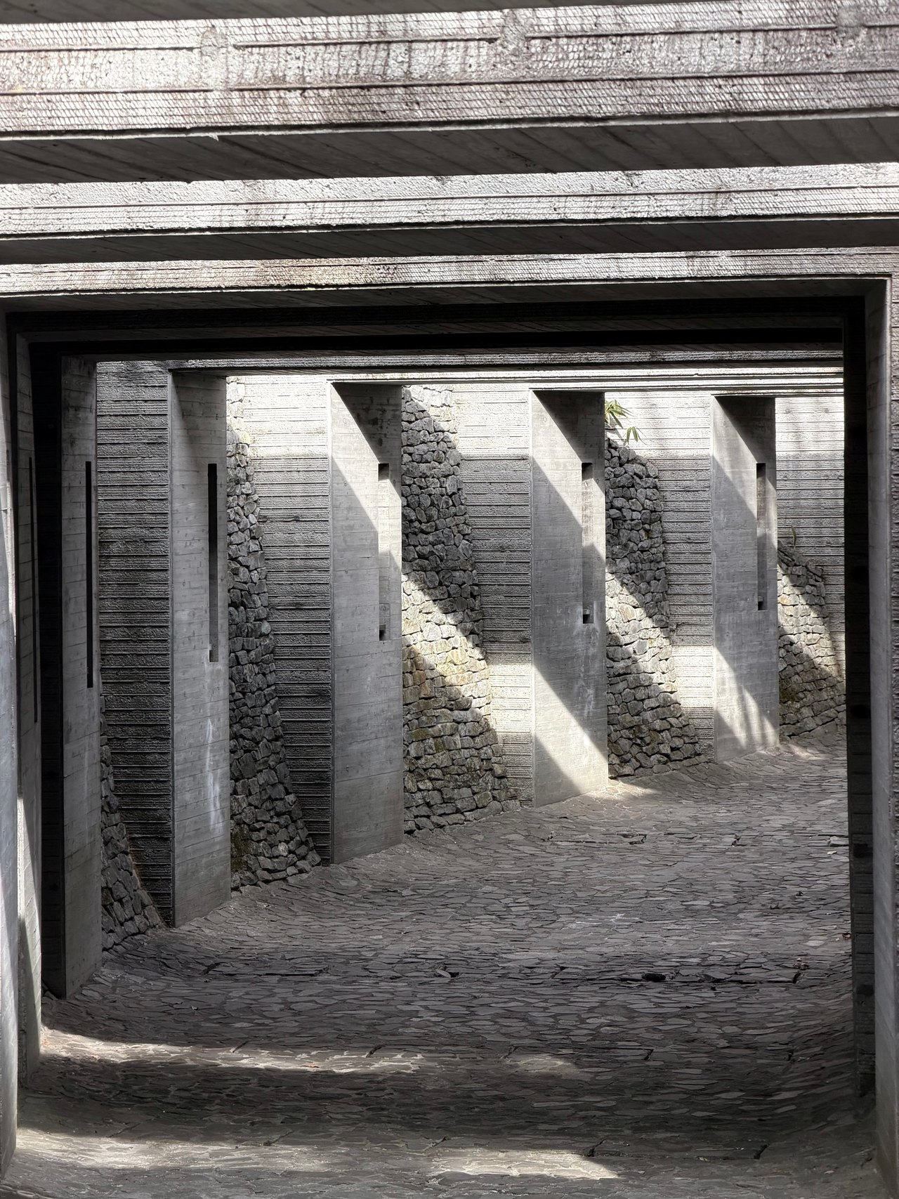 Repeated rectangular concrete frames with sunlight entering from one side