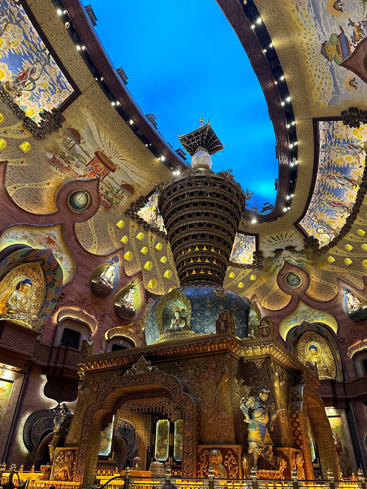 Upward view of painted vaults, statue niches, and a tiered central structure